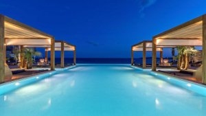 blick pber den pool auf das dunkel blaue meer im pool gibt es sitzgelegenheiten mit bänken imluxuriösen hochklassigen exklusiven designer hotel santa marina auf mykonos in griechenland europa